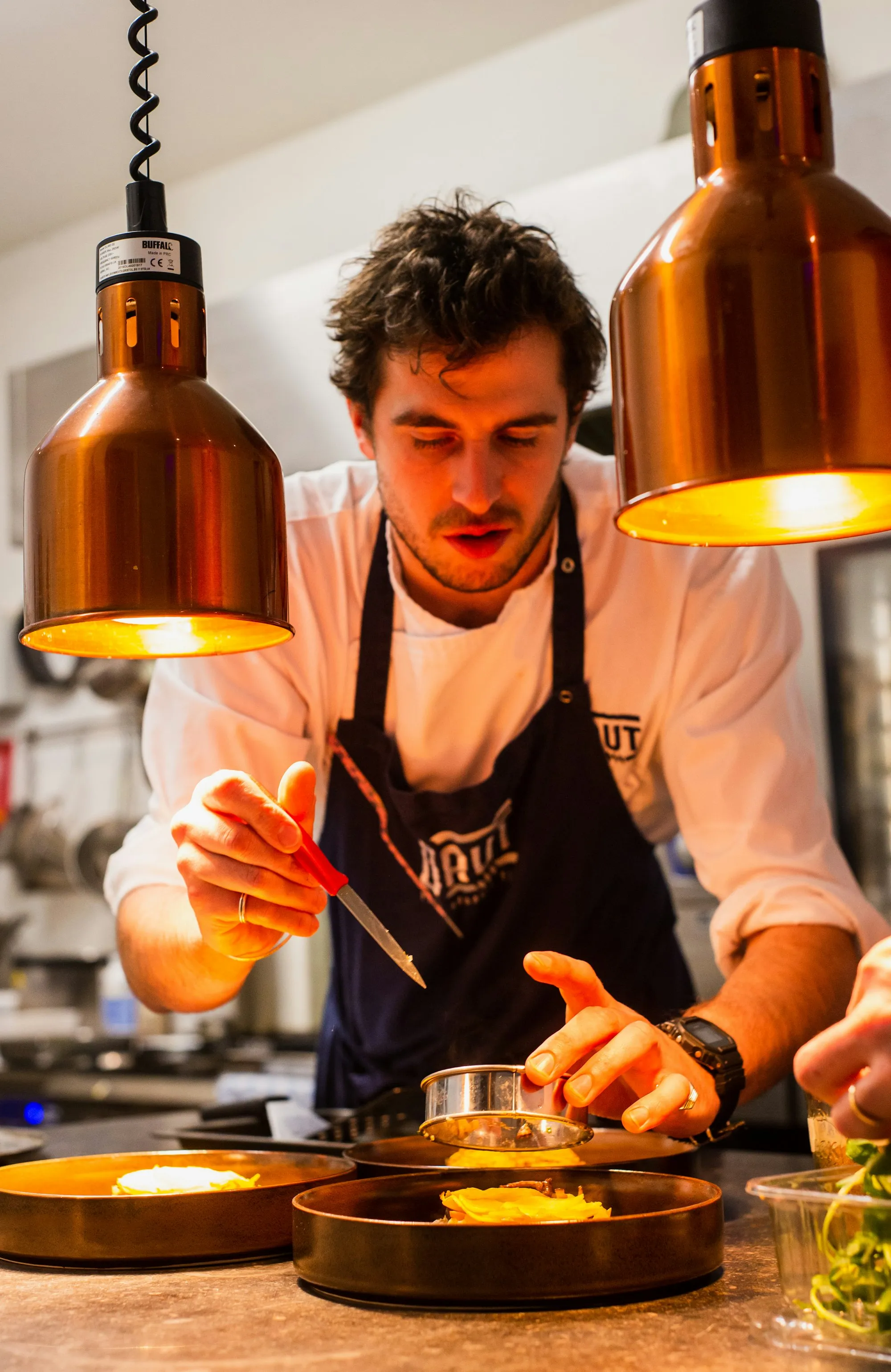 Chef cooking under copper lamps